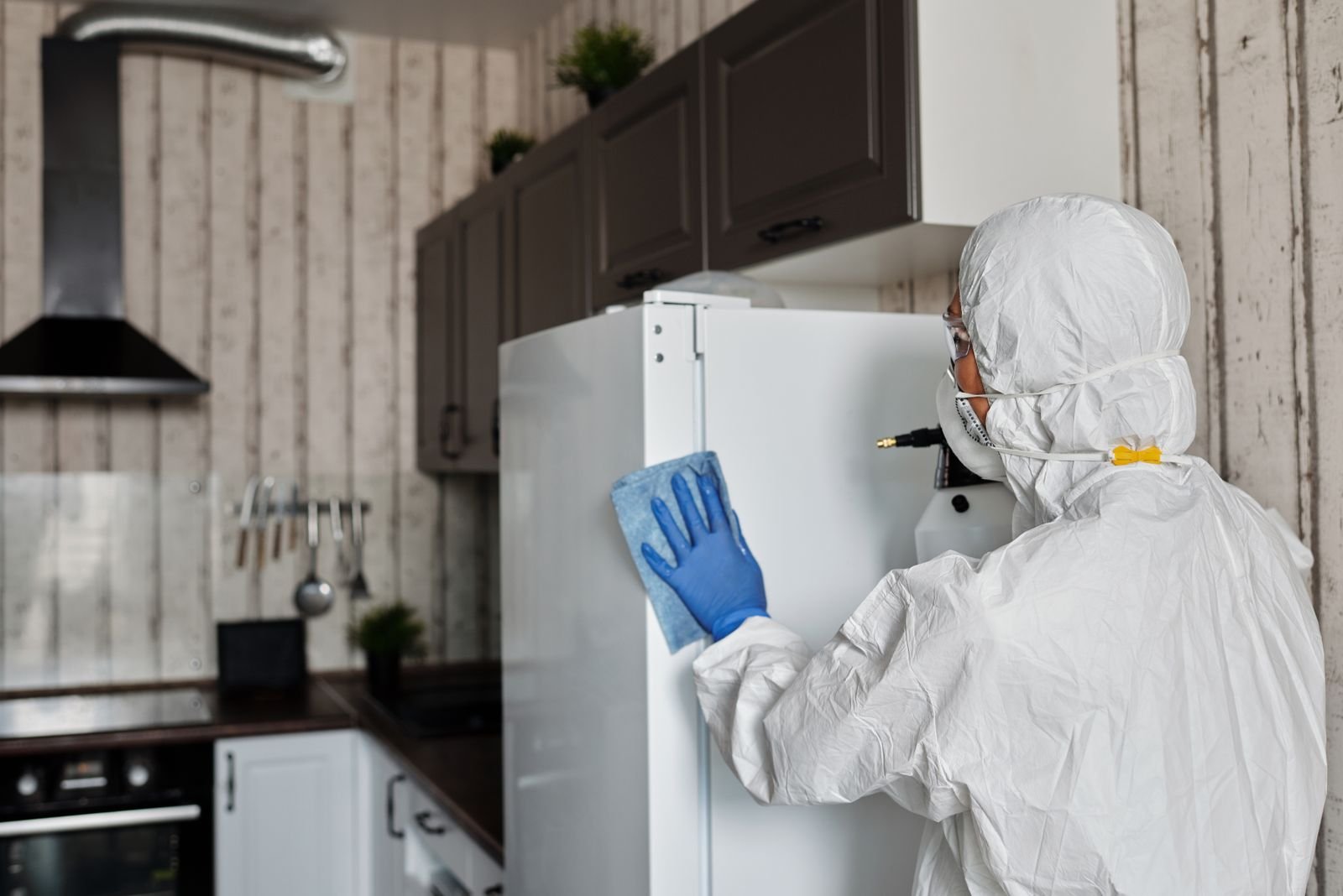 Intervenant en combinaison de protection traitant les surfaces d’une pièce