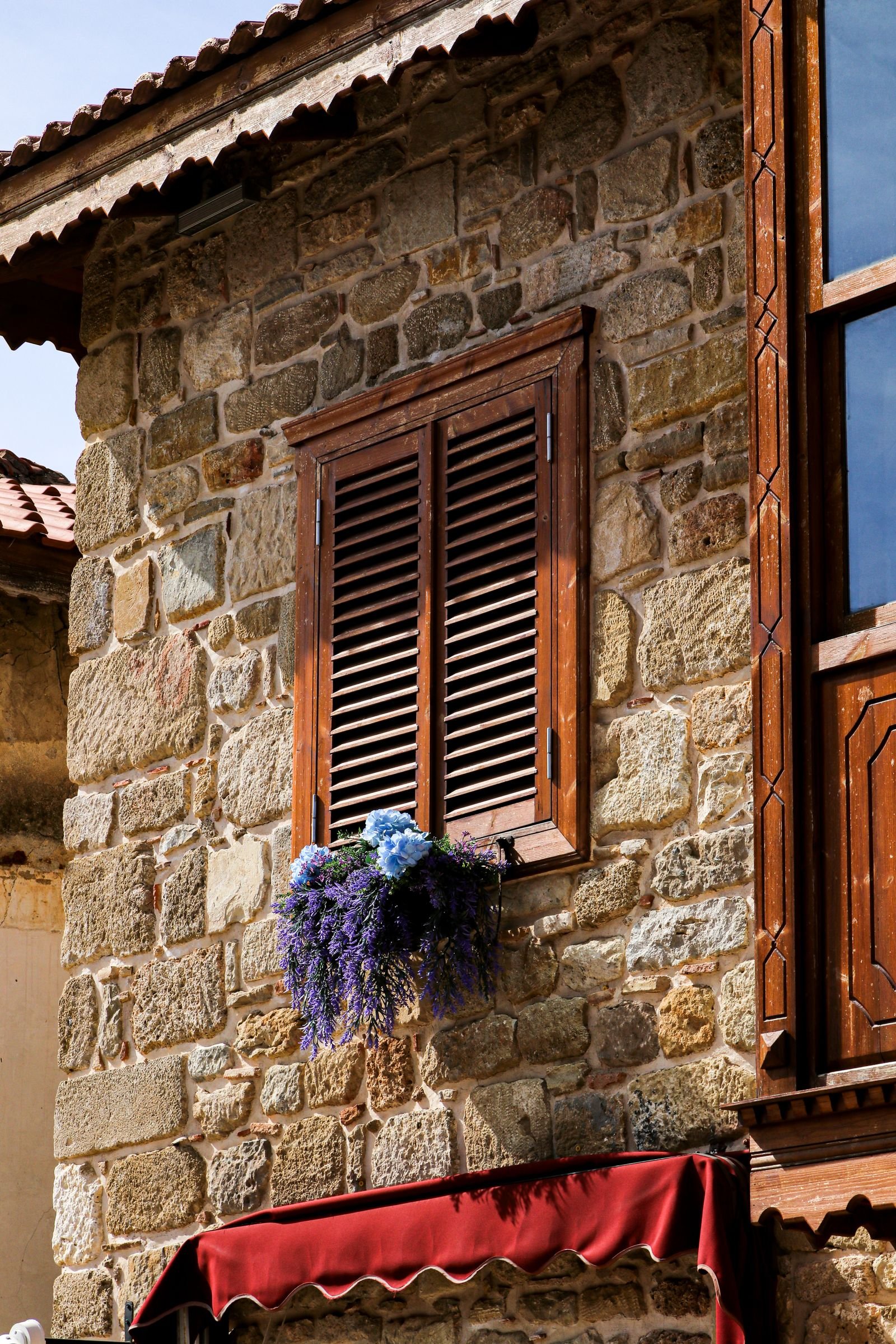 Maison en pierre à volets bois Maison provençale en pierre avec volets en bois et façade fleurie